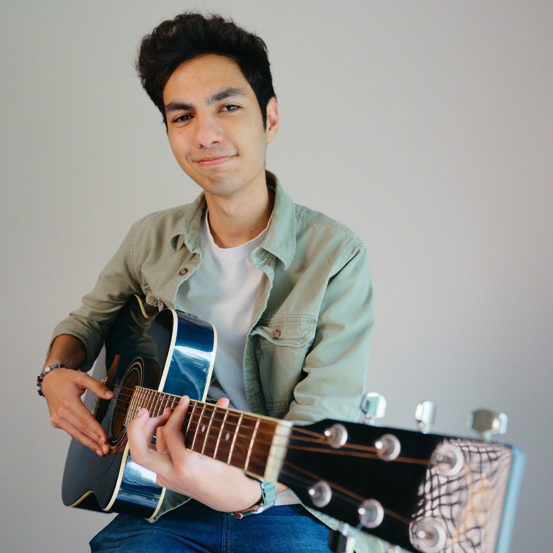 Man playing an acoustic guitar against a plain background