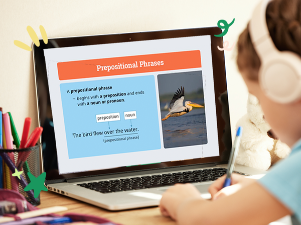 Child sitting at a desk with a laptop displaying an educational program, with various colorful papers and pencils around. Time4Learning 5th grade